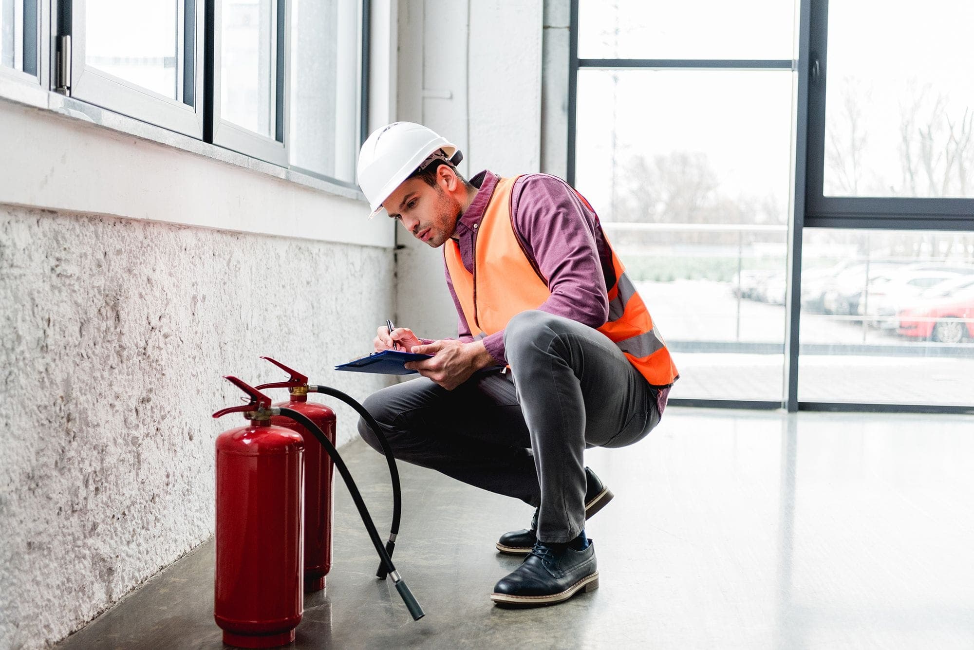 Photograph of an inspector checking off the latest month of the fire inspection record on a fire extinguisher.