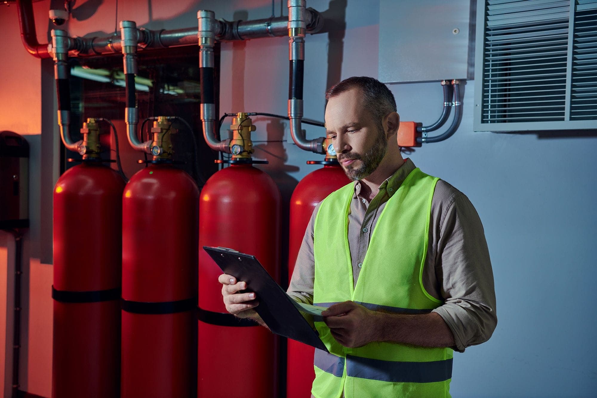 Photograph of an inspector reviewing various parts of a fire suppression system, checking off items on his clipboard.